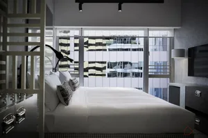 Clean, modern bedroom with a minimalist aesthetic, featuring a sleek bed with white bedding, and a large window offering city