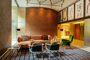 Modern hotel lobby with a textured wooden wall, contemporary furniture, and colorful artwork.