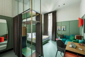 A modern hotel room featuring green paneling, curtains, and wooden furniture.