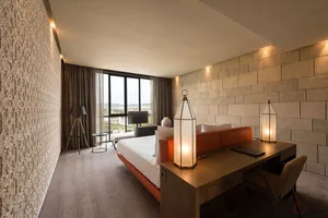 Modern hotel suite with wooden accents, concrete walls, and fabric furnishings.