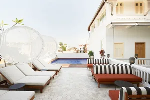 Modern hotel terrace with wooden lounge chairs, glass walls, and a cement patio