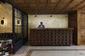 A modern industrial lobby features a brick wall, concrete floor, and wooden furniture.