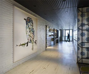 Modern indoor space with brick walls and concrete floor featuring a large abstract art piece.