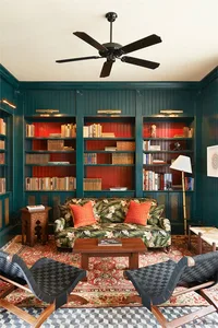 A modern interior living room library with a tropical print sofa, patterned rug, and ceiling fan.