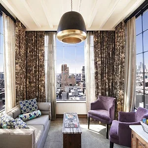 Spacious, contemporary living room featuring minimalist furniture and large windows with cityscape view.
