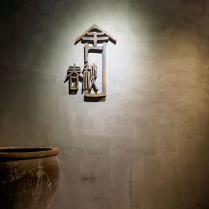 Metal sculpture with '春秋' characters mounted on a concrete wall