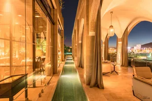 Modern residential exterior with glass terraces and lanterns at dusk, overlooking city lights.