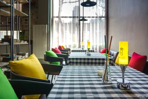 A modern restaurant setting with a black and white checkered tablecloth, colorful cushions, and a warm yellow table lamp.