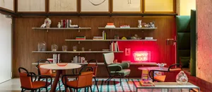 A modern restaurant interior featuring wooden walls and shelves, leather chairs, and a neon sign saying 'Happy Hour'.