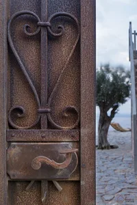 Close-up of a weathered, rustic metal door handle with intricate scrollwork.