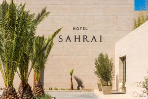 Palm trees and potted plants outside a hotel exterior.