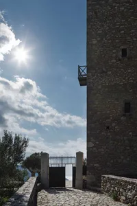 A stone tower with a metal gate and a sunlit sky in the background.