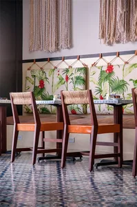 A photograph of a restaurant interior featuring textured striped polyester canvas walls, wooden chairs with orange cushions, 