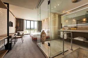 Modern hotel bedroom suite featuring marble, glass, metal, and cloth elements.