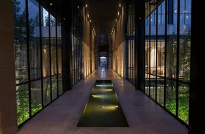 Interior corridor with modern minimalist design featuring concrete flooring and illuminated pathways.