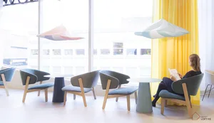 Modern, minimalist office lounge featuring sleek, contemporary seating and colorful hanging lamps.