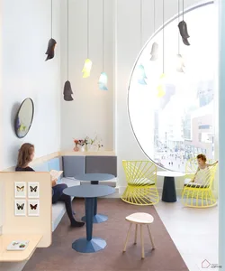 A modern restaurant interior with circular windows, colorful pendant lights, and contemporary furniture.