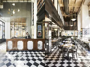 A modern restaurant interior with a checkered black and white floor, glass walls, and wooden furniture.