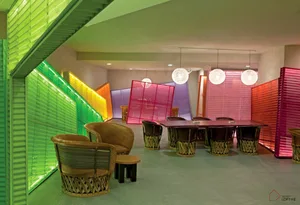 A colorful lobby with fabric dividers and woven seating, featuring a mix of green, yellow, pink, and purple shades.