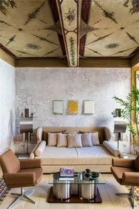A cozy living room featuring concrete walls, brick pavers, and wooden furniture.