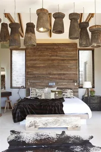 A cozy, industrial-style bedroom featuring a wooden headboard and floor-standing lamps.