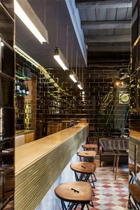 Interior view of a modern industrial restaurant bar with exposed brick walls and a polished concrete counter.