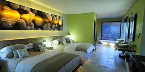 Bedroom with minimalist design featuring concrete furniture and a large wall mural of rocks and light beams.