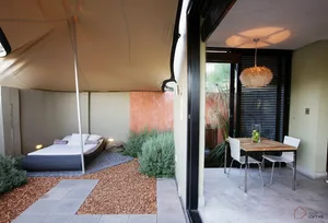 Minimalist residential patio featuring concrete flooring, wood dining table, and metal chairs.