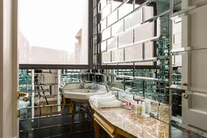 Modern bathroom featuring marble countertops, glass shower doors, and metallic finishes.
