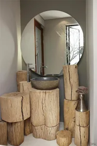 A modern bathroom features a sink made of a large wooden bowl placed on a stand carved from a single piece of wood, surrounde