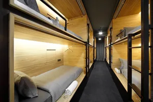 A modern bedroom with wooden bunk beds, grey bedding, and black carpet.