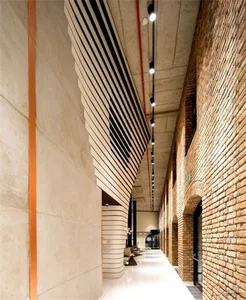 Modern architectural design featuring brick walls, concrete columns, and vertical blinds in a corridor.