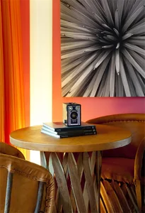 A stylish modern living room with a wooden table, chairs, and a colorful abstract artwork on the wall.