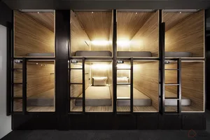 Minimalist sleeping space featuring wooden bunk beds in a capsule hotel room.
