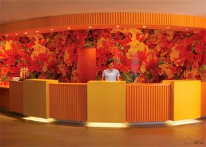 A modern reception desk adorned with vibrant orange floral wallpaper.