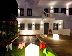 A modern residential building with a wooden deck and lighting fixtures at night.