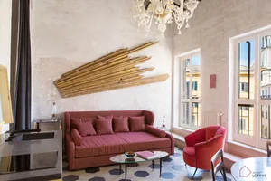 A modern living room with a red sofa, wooden wall art, and glass coffee table.