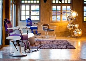 A modern, industrial-style barber shop interior with metal chairs, wooden accents, and a mix of contemporary and classic desi
