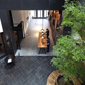 Industrial-style lobby with stone tiles, cement, and a central wooden table.