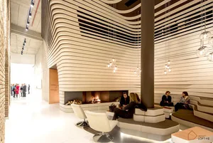A modern industrial lobby with metal and wood accents, featuring a fireplace and seating areas.