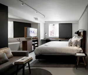 Modern, minimalist bedroom with a large bed, a cozy sofa, and a flat-screen TV.