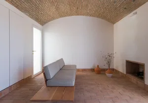 A minimalist living room with a terrazzo floor and a gray sofa.