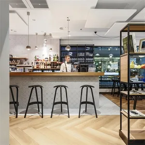 Interior design of a modern bar with wooden flooring, concrete walls, and glass elements.