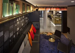 A modern coffee shop with leather seating, wooden tables, glass shelves, and metal accents.