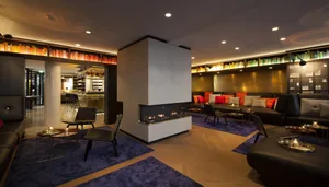 Modern hotel lobby with concrete fireplace, lounge area, and bookshelves.
