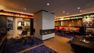 Modern hotel lobby with concrete fireplace, leather seating, and wood accents