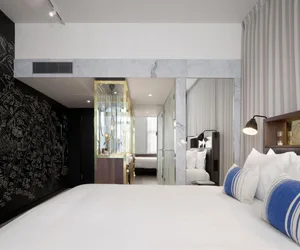 A modern hotel room with white marble accents and a comfortable bed.