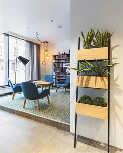 A modern industrial office space features blue armchairs and a tall standing plant holder.