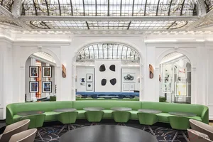 A modern reception area with a curved green seating area and round tables.