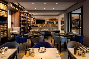 Modern restaurant interior with concrete finish, featuring contemporary furniture and a bar counter.